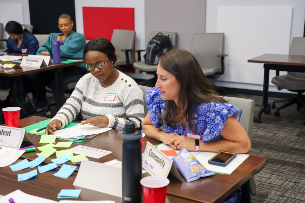 Two women engage in discussion during MCH LEEDs Program meeting.
